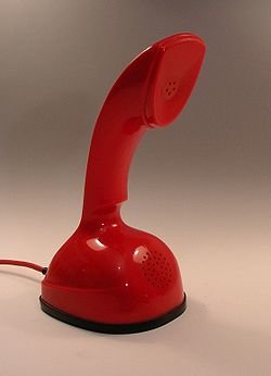 Retro röd telefon modell från 1970-talet med rundad bas och handenhet.