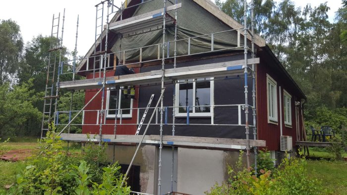 Hus under renovering med ställning, delvis nymålade väggar och bytta fönster.