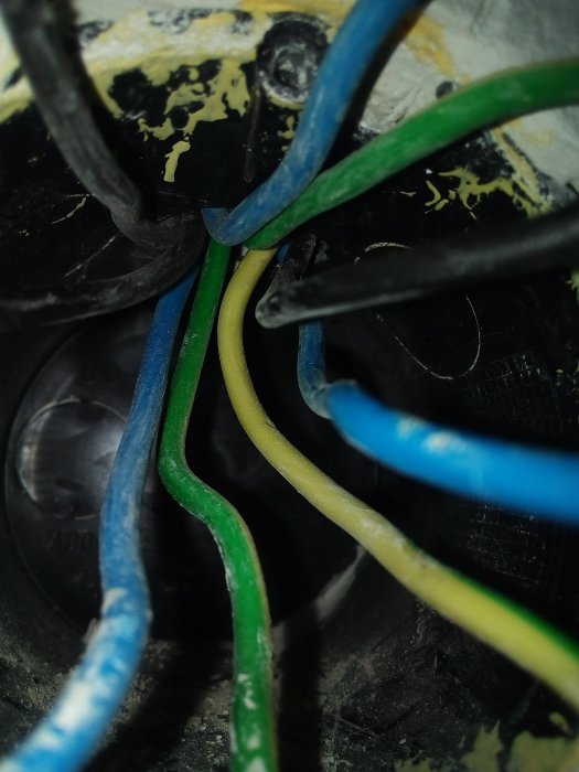 Elkablar i olika färger utan synlig takdosa inne i en vägg.