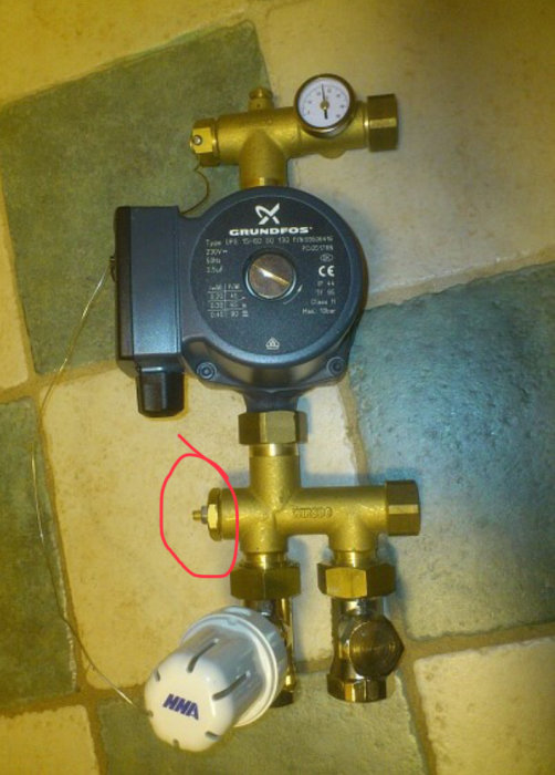 Värmesystemets shunt med cirkulationspump, manometer och justerbar ventil markerad med röd cirkel.