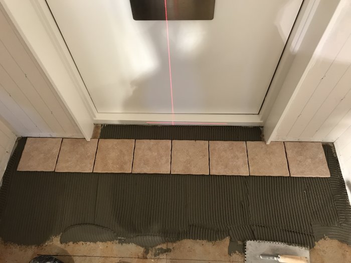 Nyinstallerade klinkers på vårdat golv, med kakelspade och framtida foglinje markerad med röd laser.