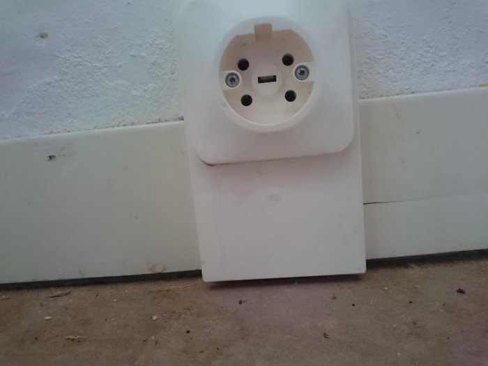 En gammal vit 400v vägguttag för spis med smutsiga märken på plintar och vägg.