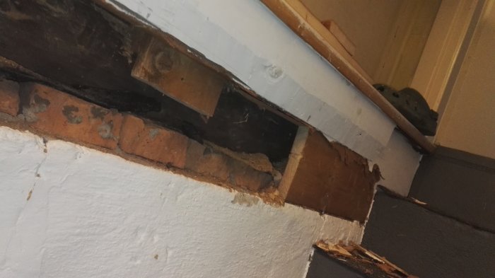 Partiellt avlägsnade masonitskivor och spån som avslöjar en trästock i en källartrappa.
