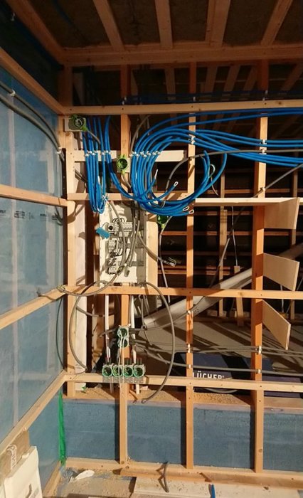 Installation av elektriskt system med blåa kablar och dosor i en vägg under konstruktion.