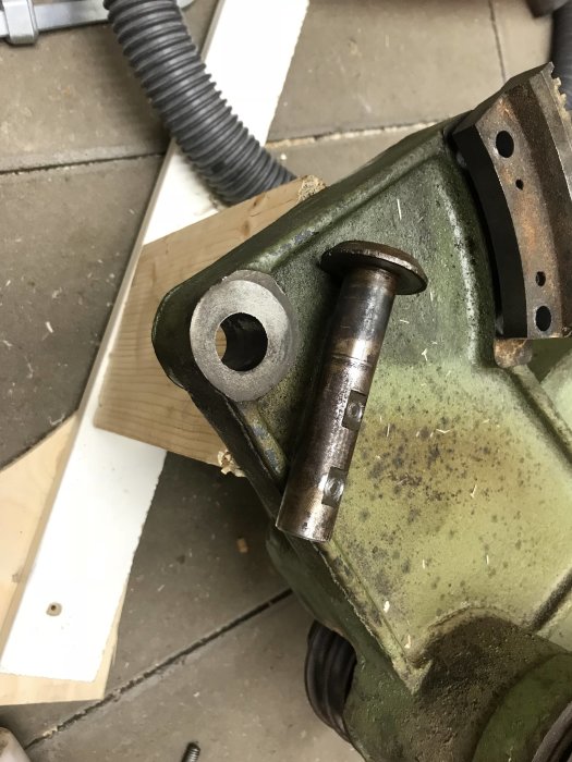 Skruvstäd som pressar en metallpinne in i trä, med märken på träet från käftarna.