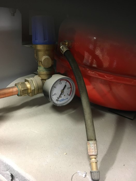 Manometer med noll tryck bredvid röd expantionskärl och rörkopplingar.