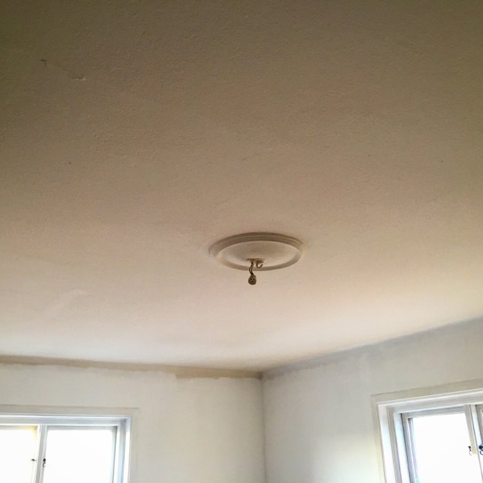 Nymålat vitt tak med en enkel taklampa, ger intrycket av högre takhöjd.