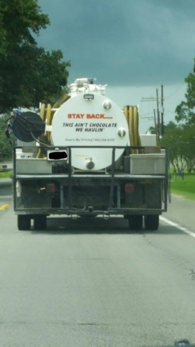 Lastbil med släpvagn och tank märkt "STAY BACK THIS AIN'T CHOCOLATE WE HAULIN'" på väg.