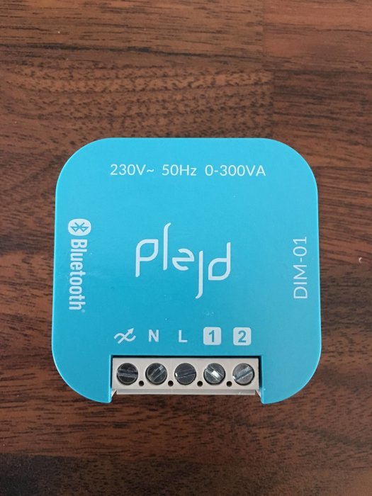 En Plejd dosdimmer med blå etikett, kopplingsplintar, och märkningar för 230V och Bluetooth.