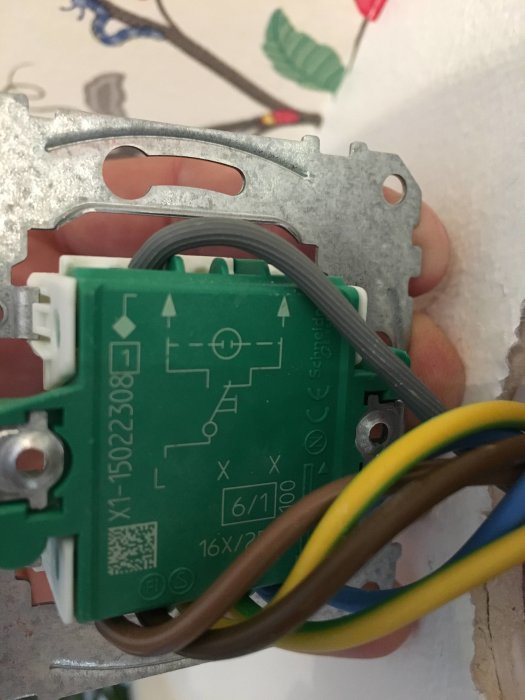 Elektrisk dosdimmer med anslutna kablar monterad i en dosa med grå, brun och blå sladdar synliga.
