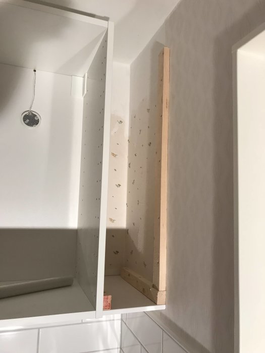 Trähörn och sidopassbitar installerade vid vitt köksskåp under renovering.