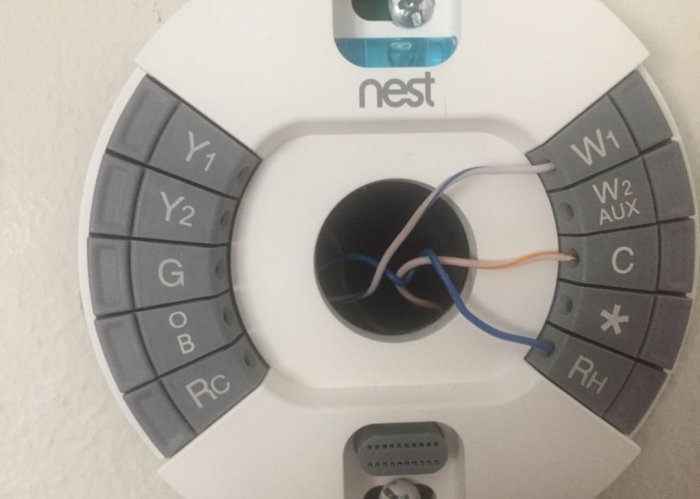Nest Learning Thermostat med öppen panel och exponerade kablar för installation.