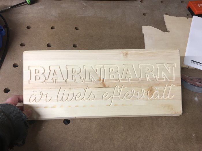 Träskyl med texten "Barnbarn är livets efterrätt" i en verkstadsmiljö.