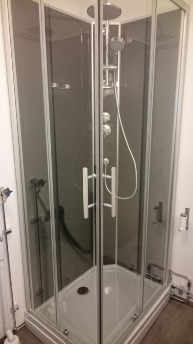 Nyinstallerad hörndusch med genomskinliga dörrar och kromade detaljer, monterad i ett renoverat badrum.