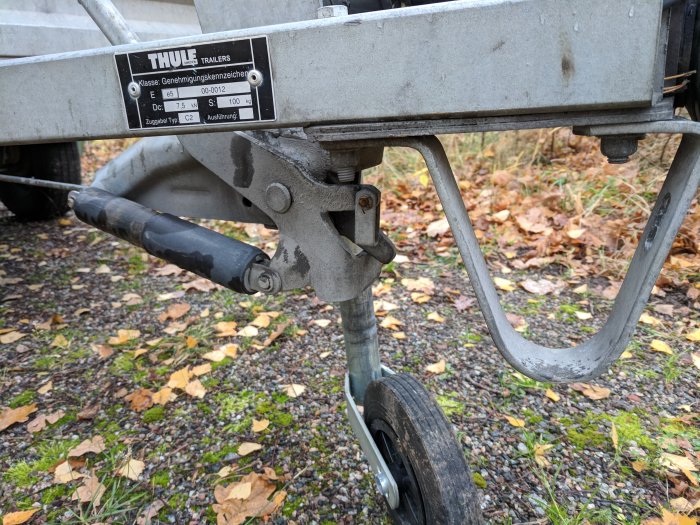 Släpvagnens dragstång med avsliten säkerhetsvajer och ett Thule-märke.