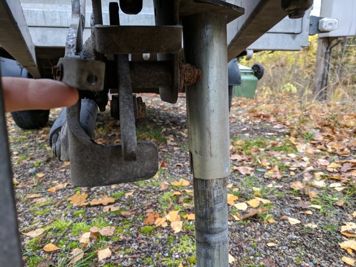 Närbild av ett släpvagnsfäste med en avsliten säkerhetsvajer och synlig korrosion.