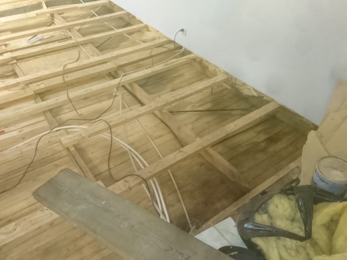 Oöppnat mellanbjälklag med synliga träreglar och isoleringsmaterial i ett pågående renoveringsprojekt.