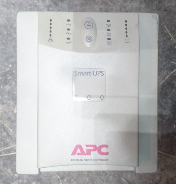 APC Smart-UPS-enhet utan fungerande batterier som står på ett golv, använd skick, klar för återvinning.