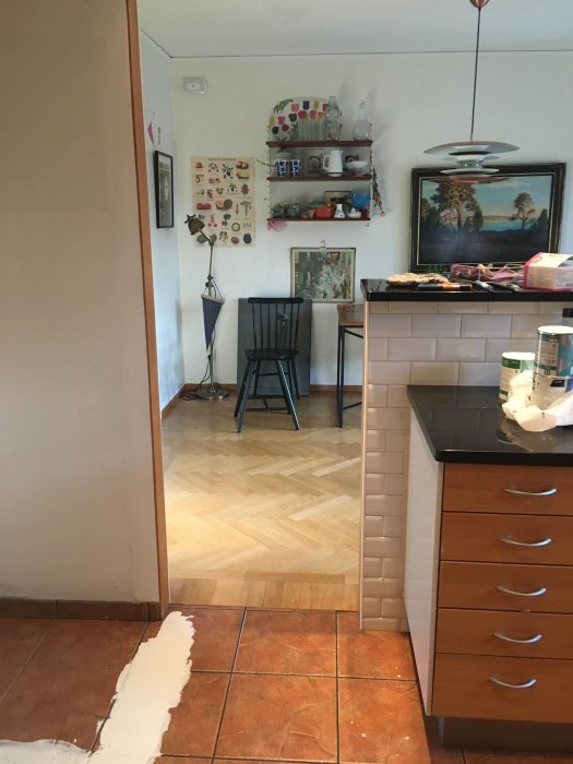 Kök med parkettgolv och terrakottaplattor, möbler och dekorationer, vägg utan synligt vattenuttag.