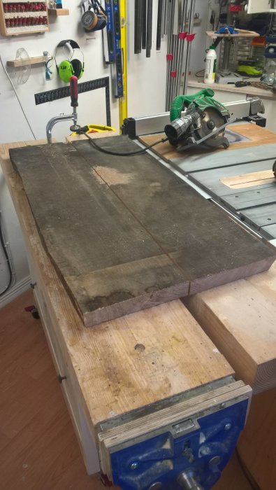 Ekplankor förberedda för att tillverka ett klaffbord, upplagda i en verkstad med såg.