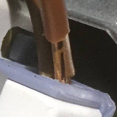 Avskalade elektriska kablar med synlig koppar som behöver åtgärdas inuti en anslutningsdosa.