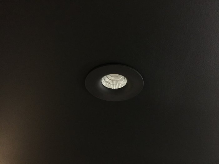 Svart tak med en infälld svart spotlight riktad nedåt.