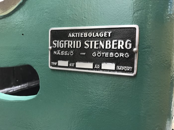 Färdigmålad grön maskindel med märkplåt från "Aktiebolaget Sigfrid Stenberg" mot en svart bakgrund.
