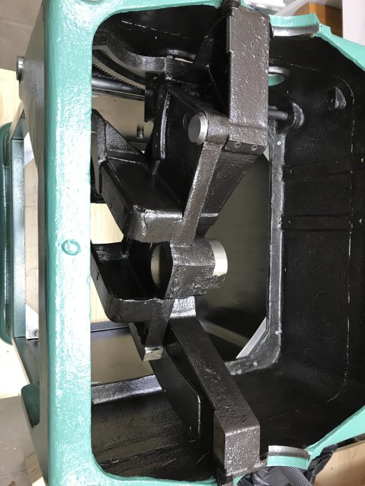 Delvis ihopsatt såg med nyligen målade svarta och gröna metalldelar, med fokus på tiltaxelns ändstopp.