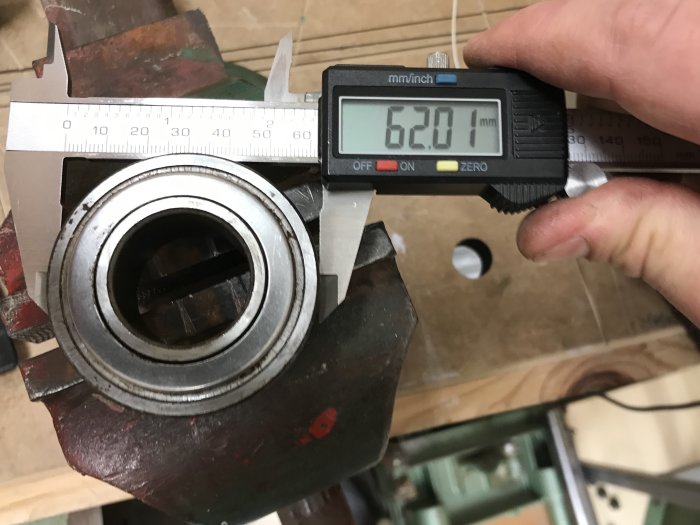 Skjutmått visar 62,01 mm på en borttagen lagerenhet under renovering.