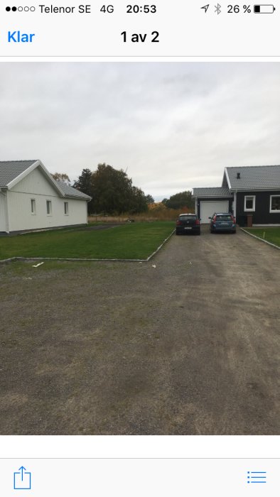 Ojämn grusuppfart utvidgad för framtida dubbelgarage, med hus och bilar i bakgrunden.