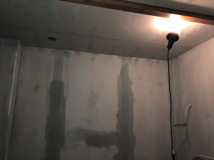 Nyinstallerat innertak med spackling på väggarna under arbete, synlig taklampa och ledningar.