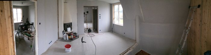 Panoramavy av en övervåning under renovering, elinstallationer och väggskivor pågår.