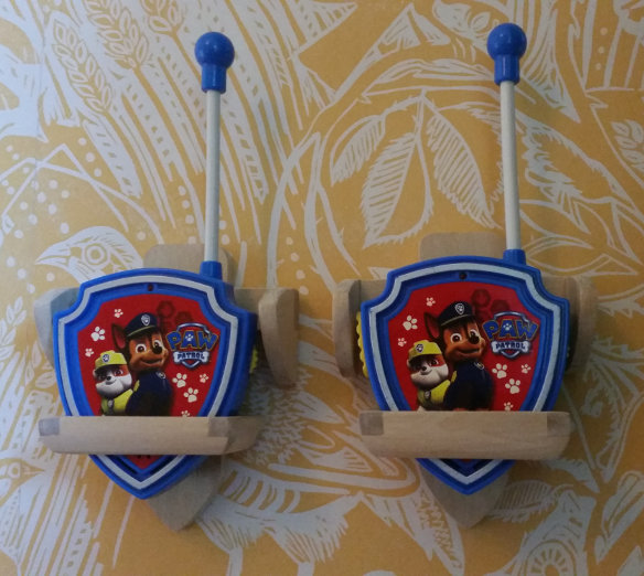 Två handgjorda walkie-talkie hållare med Paw Patrol-tema fästa på en tapetserad vägg.