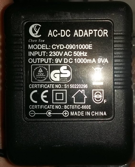 AC-DC adapter med specifikationer: 9V DC 1000mA 9VA, modellnummer och certifieringar.