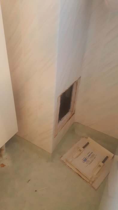 Hål i vägg under trappa där inspektionslucka ska monteras för att nå vattenrör.