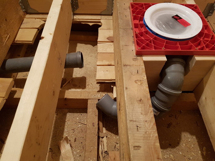 Installation av avloppsrör mellan golvbjälkar i ett pågående byggprojekt utan håltagning.