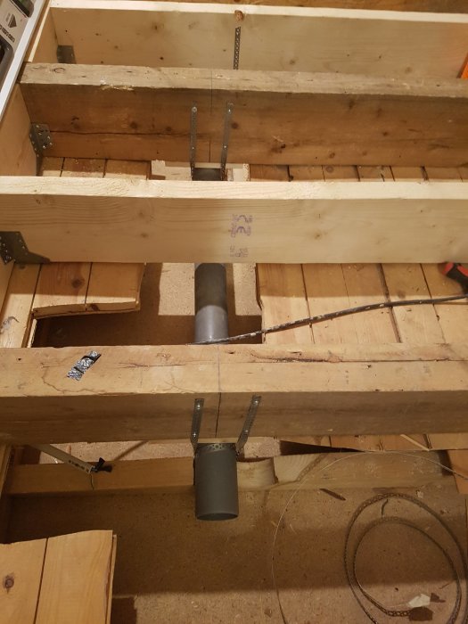 Golvbjälklag med öppen konstruktion och synliga ventilationsrör i ett pågående byggprojekt.