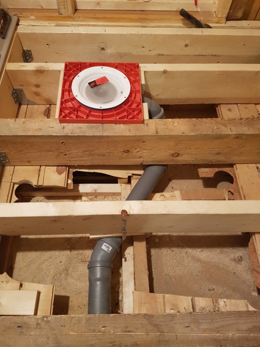 Installation av avloppsrör och golvbrunn i träbjälklag under pågående renovering.