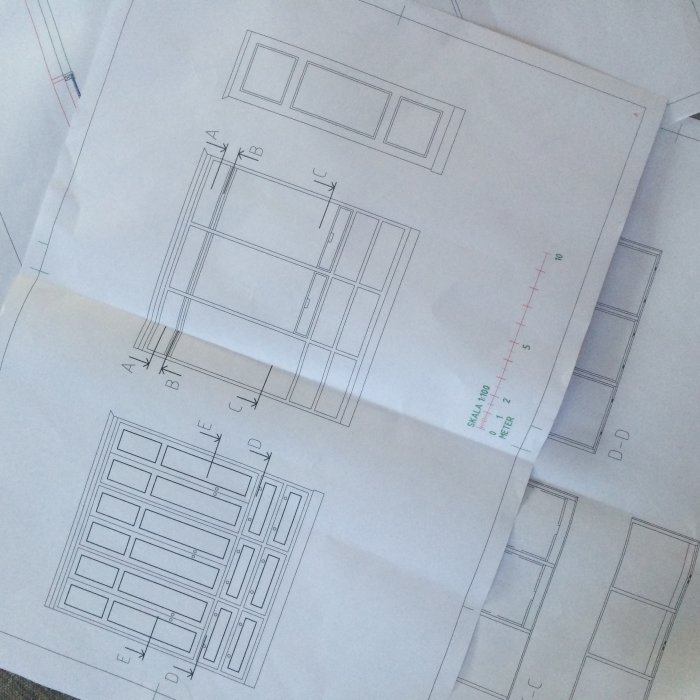 Handritade skisser av platsbyggda garderober med måttangivelser, liggande på ett bord.