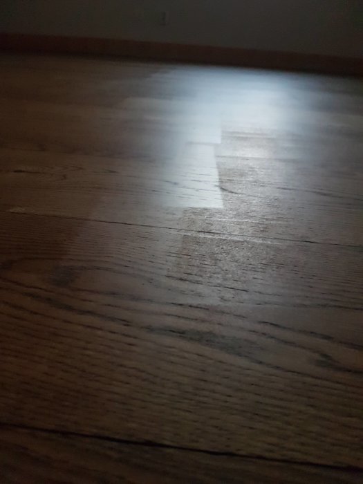Dimmigt vardagsrum fotograferat på morgonen med synligt trägolv och ljusstråle.
