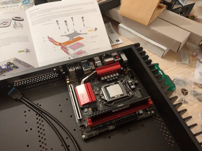 Moderkort installerat i chassi med heatpipes och uppackade datordelar i bakgrunden.