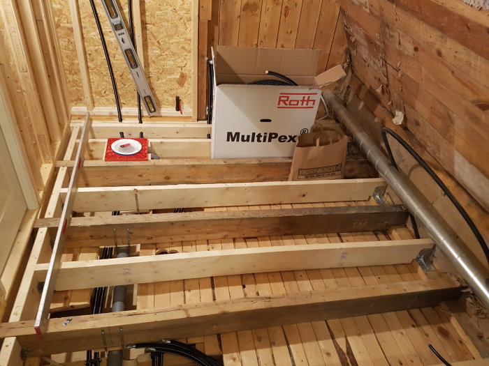 Ny och gammal golvregelkonstruktion med mått ca 250 längd, vattenpass och byggmaterial i bakgrunden.