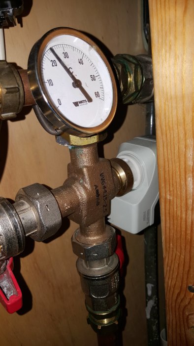 Värmesystems mätare och ventiler med texten "Grundfos" på pumpen och en temperaturmätare.