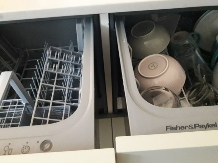 Inuti en Fisher & Paykel diskmaskin med disk och glas, synlig stödskiva mellan uppställda enheter.