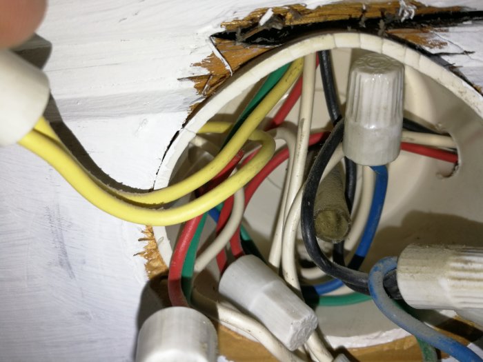 Elkablar i olika färger kopplade med kabelskor och isoleringshylsor inne i en väggdosering.