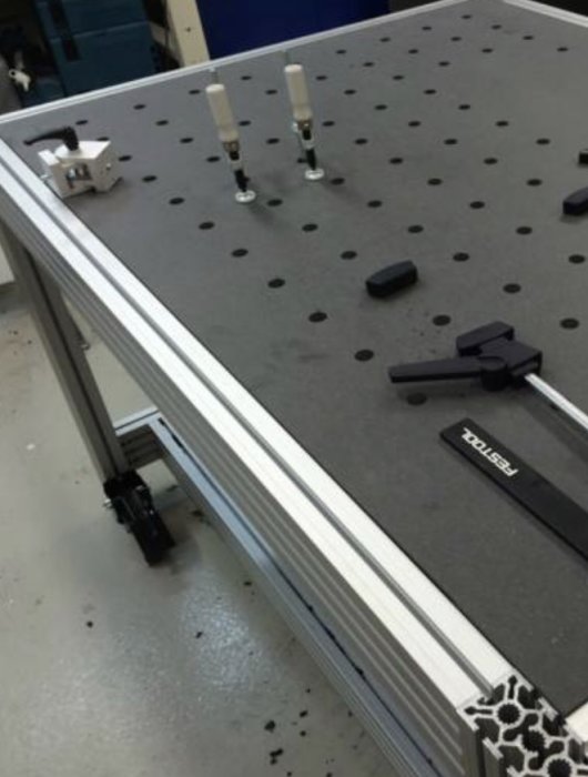 Verktygsbord med höj- och sänkbara hjul, arbetsstycken och T-spårklämmor.