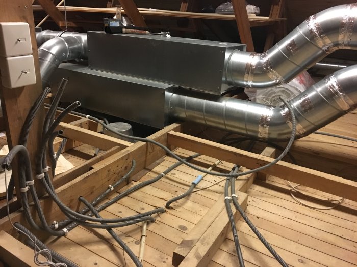 Öppet bjälklag med synliga elinstallationer och ventilationssystem i form av flexibla rör och metallkanaler.