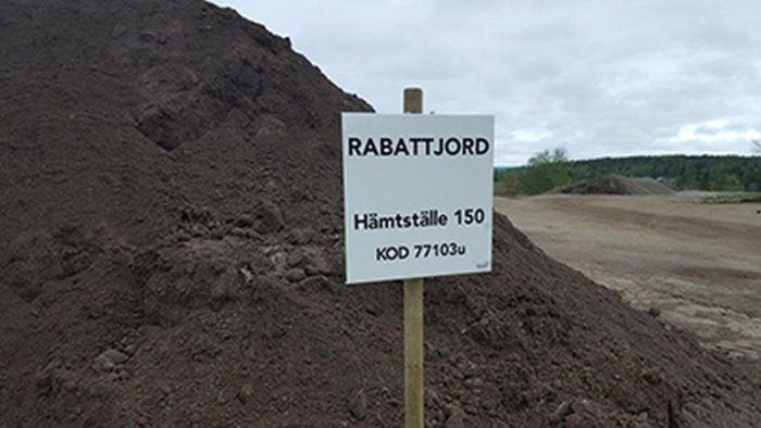 Skylt märkt "RABATTJORD" framför en stor hög med jord på ett hämtställe.