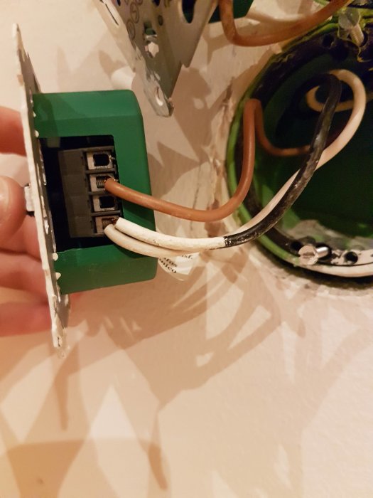 Öppen eldoslåda med en dimmer, två vita och en svart kabel synliga, vägginstallation.