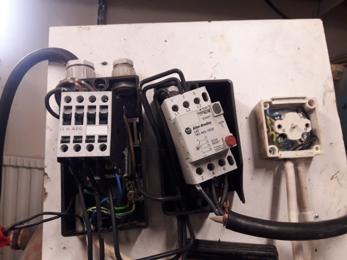 En bild av en öppen elektrisk panel med avklippta kablar och olika komponenter som kontaktorer och motorskydd.
